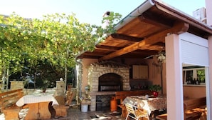 Un patio esterno con camino in pietra, mobili in legno e pavimento piastrellato.