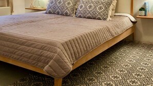 A bedroom with a bed, patterned pillows, a round mirror, bedside lamps, and a patterned floor. - Strandhaus am Wasser by Interhome (Altwarp)