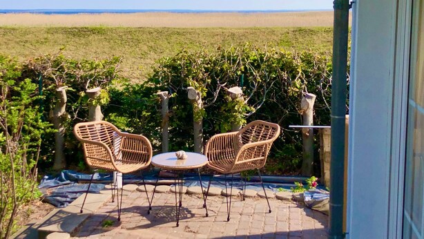 An outdoor patio with two wicker chairs and a small table, overlooking a grassy field and a distant horizon. - Strandhaus am Wasser by Interhome (Altwarp)