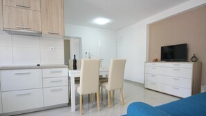 Una cocina moderna con armarios blancos y una zona de comedor con dos sillas.