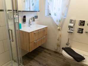 Et badeværelse med en trækommode, vask, toilet og bruseområde.