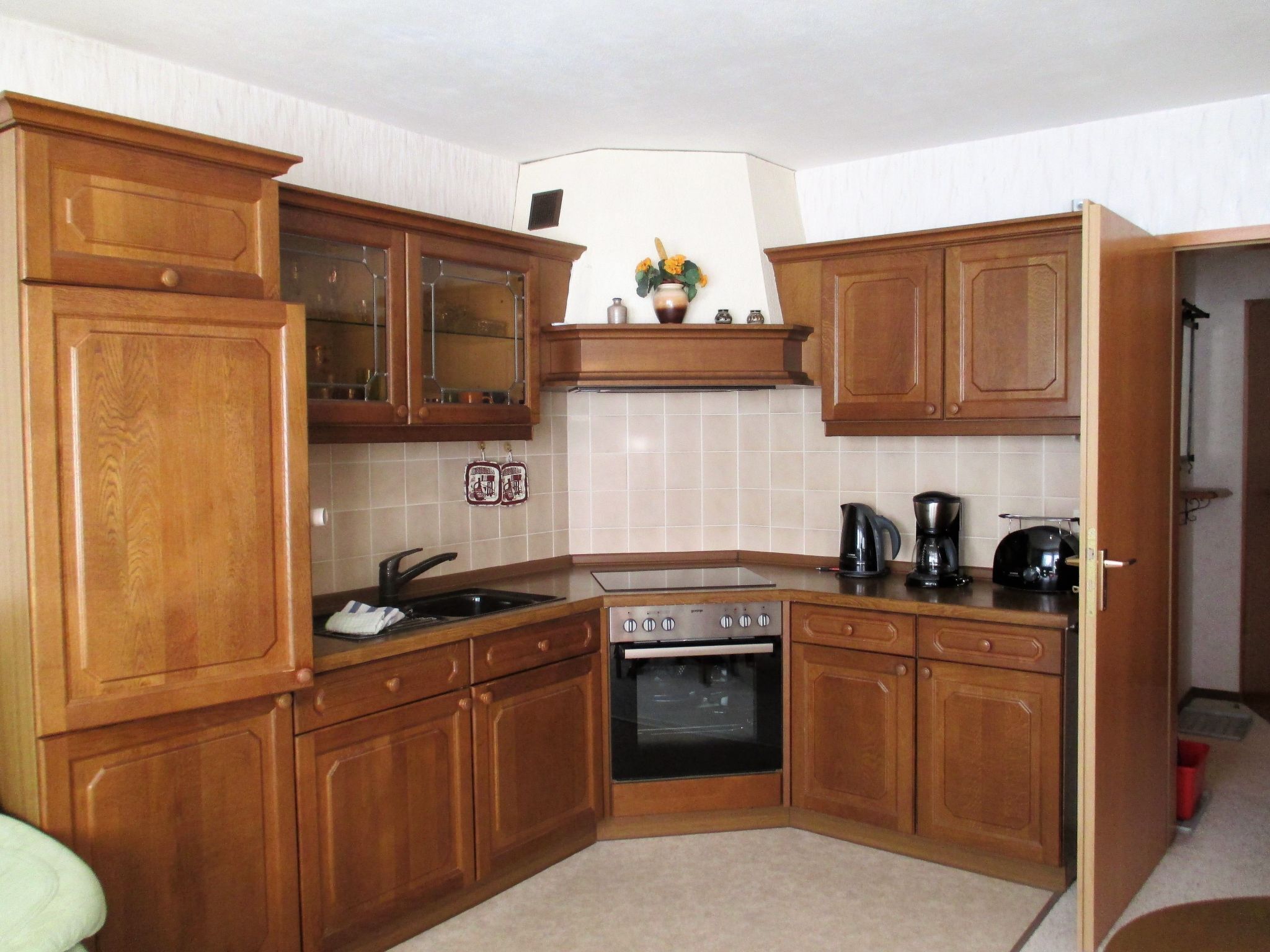 Una cocina con armarios de madera, estufa, fregadero y cafetera.