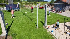 En baghave med volleyballnet, trampolin og sandkasse.
