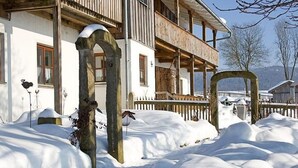 A snow-covered building with a wooden balcony and a stone archway. - Am Rückerlhof -Alexi by Interhome (Geigant)
