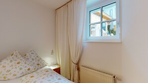 A bedroom with a bed, curtains, a window, and a radiator. - Christine by Interhome (Bischofswiesen)