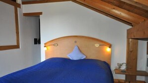 Ein Schlafzimmer mit einem hölzernen Kopfende, einer blauen Bettdecke und einem kleinen Nachttisch mit einer Lampe.