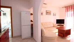 A compact living space with a kitchenette, a sofa, a TV, and a dining table. - in Baška mit Eigenem Balkon by Interhome (Krk/Baška)
