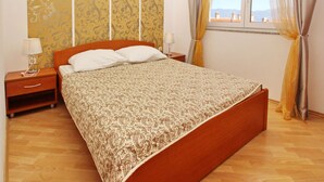 Une chambre à coucher avec un lit en bois, deux tables de chevet, une fenêtre avec des rideaux et un papier peint à motifs.