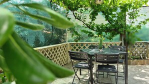 Un patio con mesa y sillas, rodeado por una cerca de celosía y follaje.
