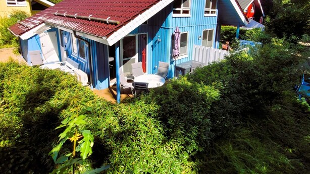 A blue house with a red roof, a chimney, and a small patio with outdoor furniture. - Vacation home Sophie by Interhome (Extertal)