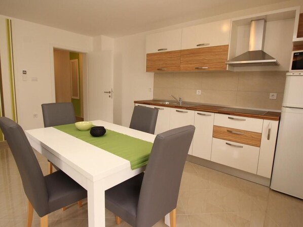 Een moderne keuken met witte kasten, een houten aanrechtblad en een roestvrijstalen afzuigkap.