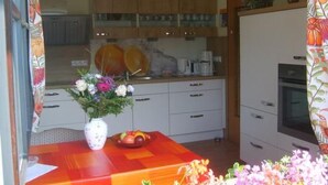 Et køkken med træskabe, et spisebord med en vase blomster og en skål med frugt.