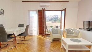 Ein modernes Wohnzimmer mit Essbereich, Fernseher und Blick auf Berge.