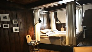 Ein gemütliches Zimmer mit einem Bett, einem Sessel, einem Fellteppich und gerahmten Bildern an der Wand.