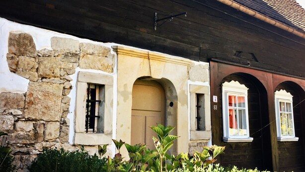 Ein Gebäude mit einer Stein-Fassade, einem Holzvordach und bogenförmigen Eingängen.