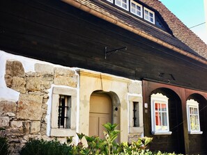 Un bâtiment doté d’une façade en pierre, d’une avancée en bois et de portes en arc de cercle.