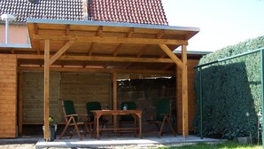 Una pérgola de madera con una mesa y sillas en un patio trasero.