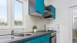 Una cucina moderna con mobili color petrolio, un lavello in acciaio inossidabile e un forno integrato.