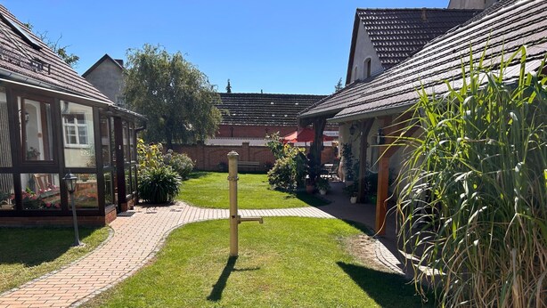 A courtyard with a central lawn, brick pathways, and surrounding buildings with tiled roofs.