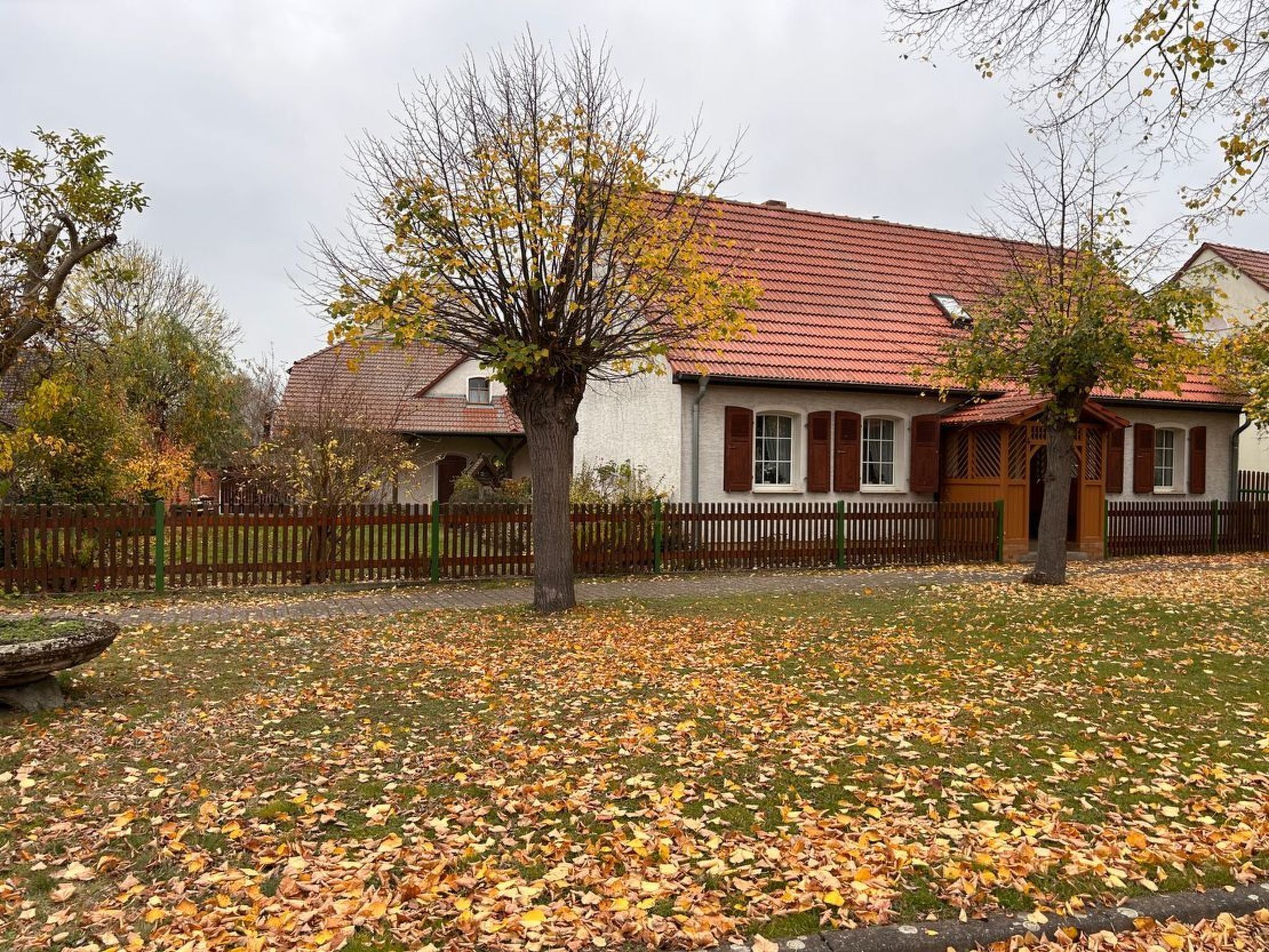 A house with a red tiled roof, white walls, and a wooden fence.