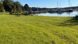 A marina with boats docked, grassy areas, and trees in the background.