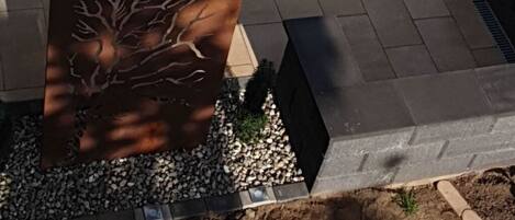 An outdoor patio area with a seating arrangement, including a sofa and chairs, a table, and a decorative metal sculpture.