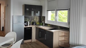 A modern kitchen with black cabinets, a stainless steel refrigerator, and a window with a view of greenery. - Appartement in Sankt Englmar mit Großem Balkon by Interhome (Sankt Englmar)