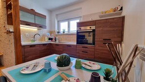 Una cocina moderna con armarios de madera, microondas y una mesa de comedor con platos, cubiertos y una sandía.