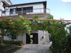 A two-story building with a stone facade, a balcony with black railings, and a vine-covered pergola. - Appartement mit Balkon und Meerblick by Interhome (Crikvenica)