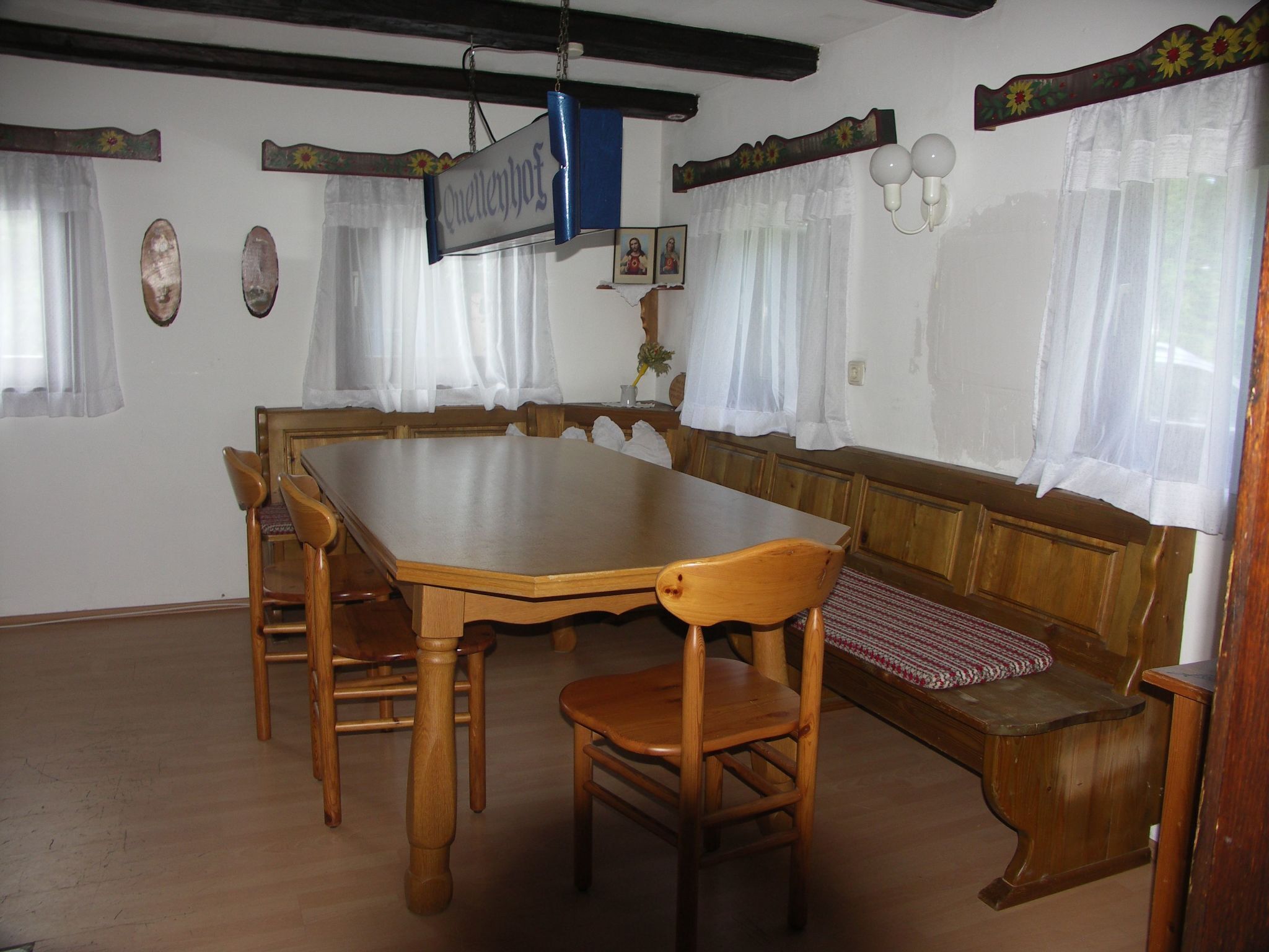 Un espace repas avec une grande table en bois, entourée de chaises et d’un banc.