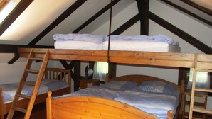 Un dormitorio tipo loft con una cama litera de madera, una escalera de madera y una pequeña silla de madera.