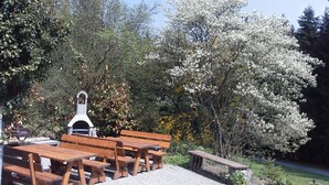 A picnic area with wooden benches and a grill, surrounded by trees and a clear sky. - Altes Bauernhaus by Interhome (Kollnburg)