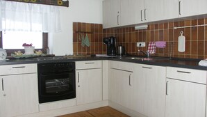 Una cocina con armarios blancos, una estufa negra y un salpicadero de azulejos.