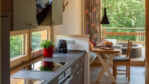 Una cocina moderna con estufa integrada, un fregadero y ventana con vista a un balcón.