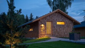 Una cabaña de madera con techo inclinado, puerta principal y una ventana pequeña.