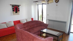 Un salon avec un canapé rouge, une table basse en verre et un tapis à rayures.