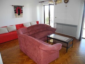 A living room with a red sofa, a glass coffee table, and a striped rug. - für 4 Personen by Interhome (Crikvenica)