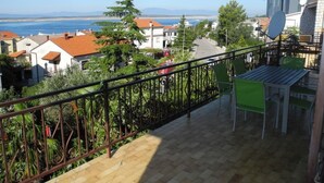 Un balcon donnant sur une ville côtière, avec une table et une chaise.