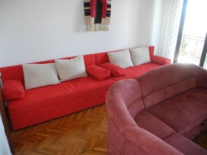 A red sofa with white cushions in a room with a wooden herringbone floor. - für 4 Personen by Interhome (Crikvenica)