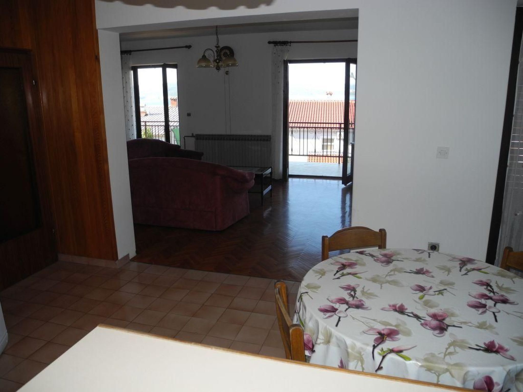 A room with a dining table, a sofa, and a view to an outdoor balcony.