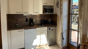 Kompakti keittiö, jossa on valkoiset kaapit, mikroaaltouuni, kahvinkeitin ja astianpesukone.