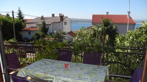 En uteplats med ett bord och stolar, med utsikt över ett bostadsområde och havet.