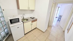 Een kleine keuken met een magnetron, spoelbak en kastjes.
