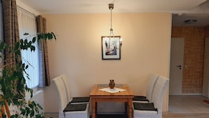 A dining area with a wooden table, two wicker chairs, a potted plant, and a framed picture on the wall. - Fewo Stricker 33 by Interhome (Walkenried)