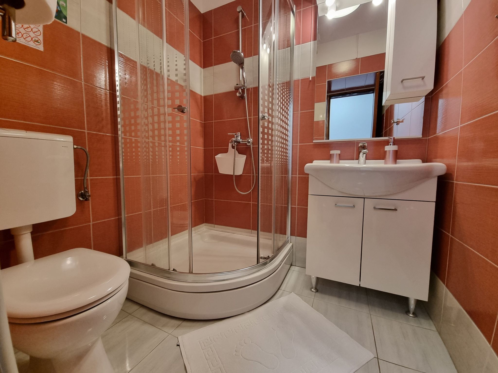 Une salle de bain moderne avec une douche à parois incurvées, des toilettes et un lavabo avec un miroir au-dessus.