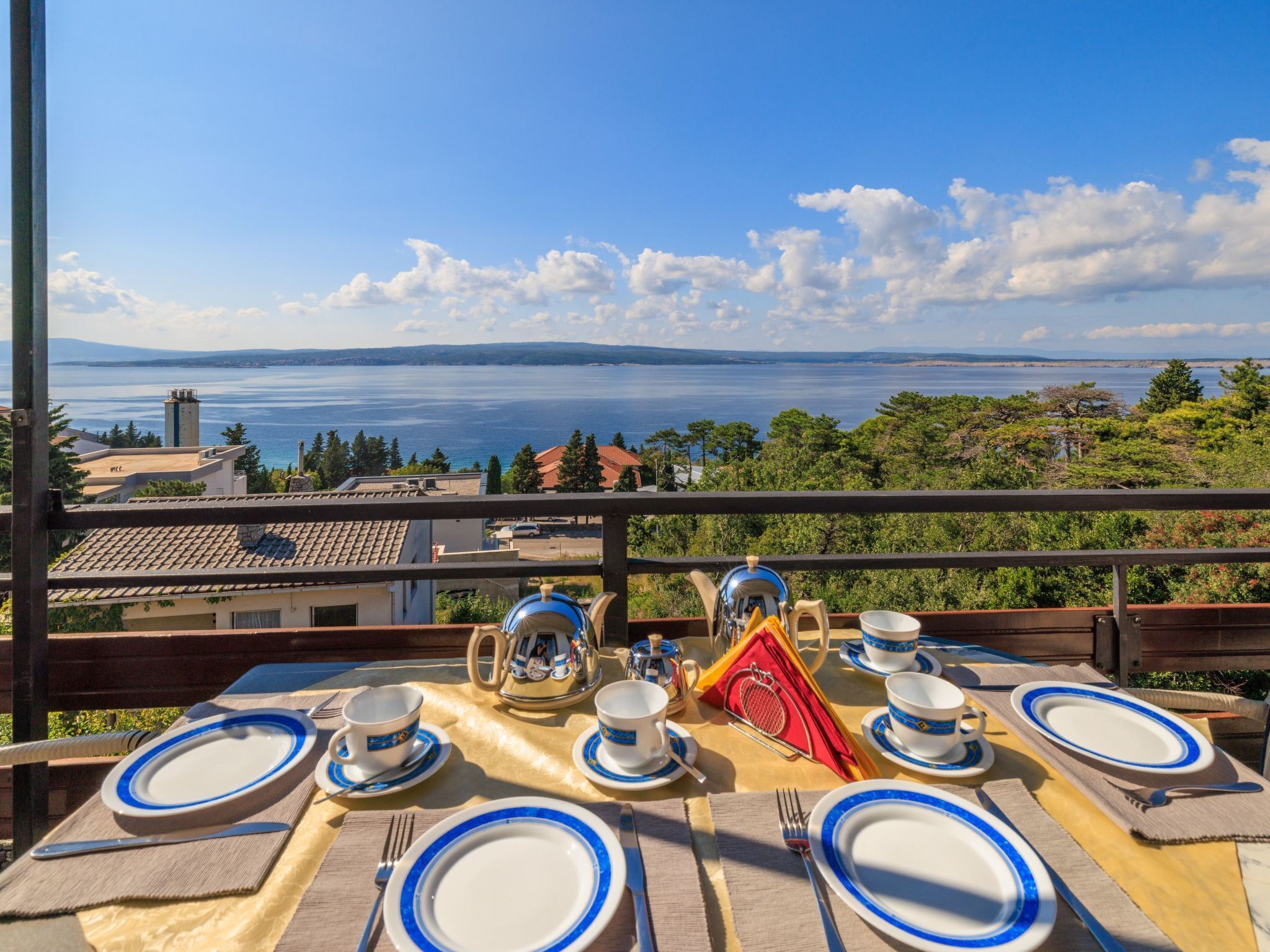 A table set for four with a scenic view of a body of water and distant mountains.