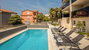 Ein Swimmingpool mit Liegestühlen und Blick auf umliegende Gebäude.