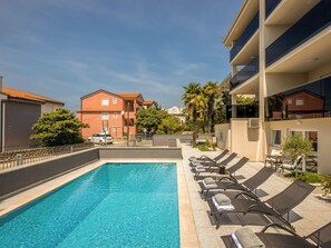 Piscina con sillas de descanso y vistas de edificios cercanos.
