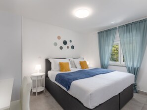 Un dormitorio moderno con una cama, mesitas de noche y una obra de arte en la pared.