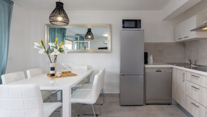 Una cocina moderna con una mesa de comedor blanca, sillas, un refrigerador y un microondas.